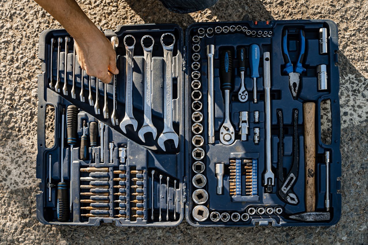 Open toolkit with assorted hand tools, including wrenches and pliers, captured outdoors.